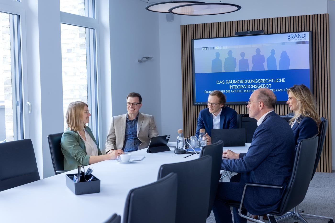 Fünf BRANDI Anwälte in einem Besprechungsraum unterhalten sich