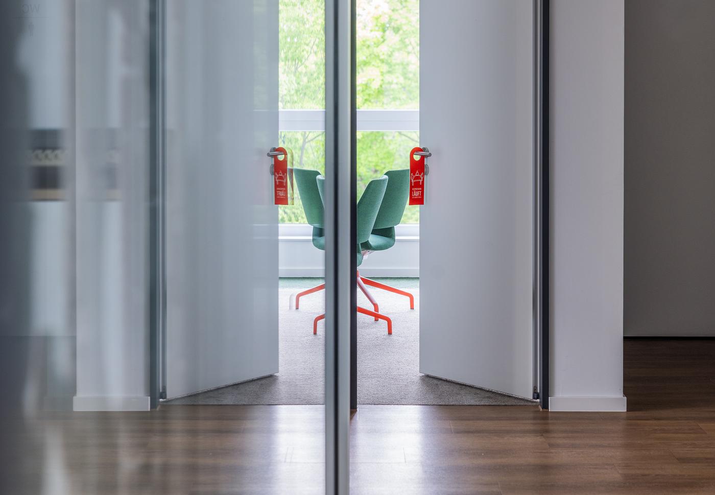 Eine offene Tür und die Stühle dahinter reflektieren im Spiegel.